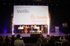 De teams van Juvoly en Valtes staan met hun cheques op het podium. Achter hen toont het scherm hun logo's.